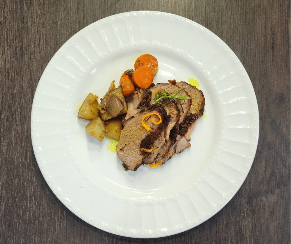 Tender roasted lamb seasoned with garlic, herbs, and warming spices with side of vegetables
